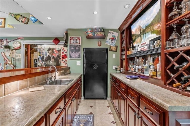 kitchen featuring recessed lighting, light countertops, freestanding refrigerator, light tile patterned flooring, and a sink