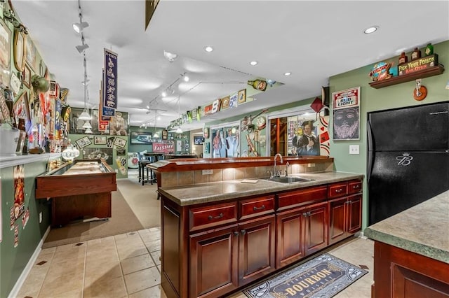 kitchen with reddish brown cabinets, recessed lighting, a sink, and freestanding refrigerator