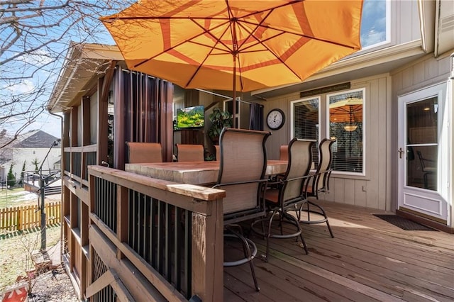 wooden terrace featuring exterior bar and fence