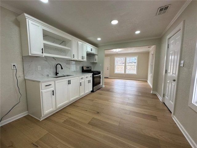 kitchen with stainless steel stove, white cabinetry, sink, decorative backsplash, and light wood-type flooring