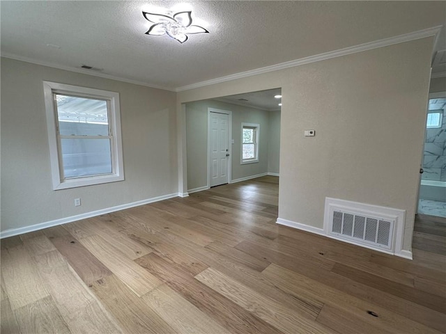 empty room featuring ornamental molding, a textured ceiling, and light hardwood / wood-style flooring