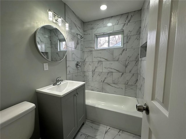 full bathroom featuring tiled shower / bath, vanity, and toilet