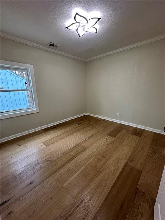 spare room featuring hardwood / wood-style floors, ornamental molding, and a textured ceiling