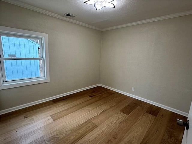 spare room featuring crown molding, a textured ceiling, and light hardwood / wood-style floors