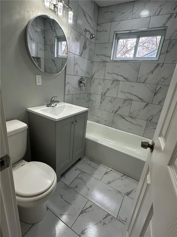 full bathroom with vanity, tiled shower / bath, and toilet