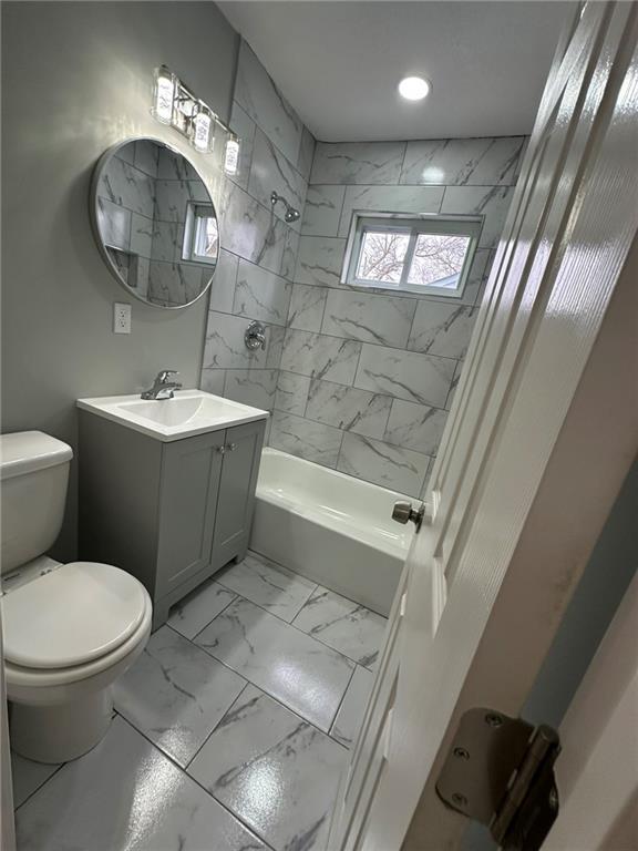 full bathroom with vanity, tiled shower / bath, and toilet