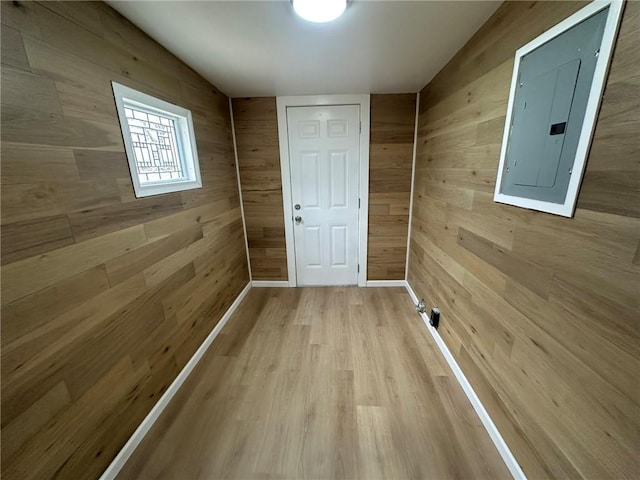 doorway to outside featuring light hardwood / wood-style flooring, electric panel, and wood walls