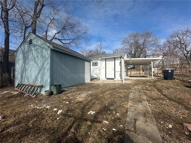 rear view of property with a carport and a storage shed