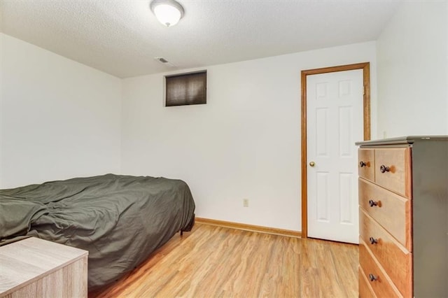 bedroom featuring a textured ceiling and light hardwood / wood-style flooring