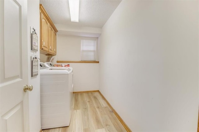 laundry room with washer and dryer, light hardwood / wood-style floors, cabinets, and a textured ceiling