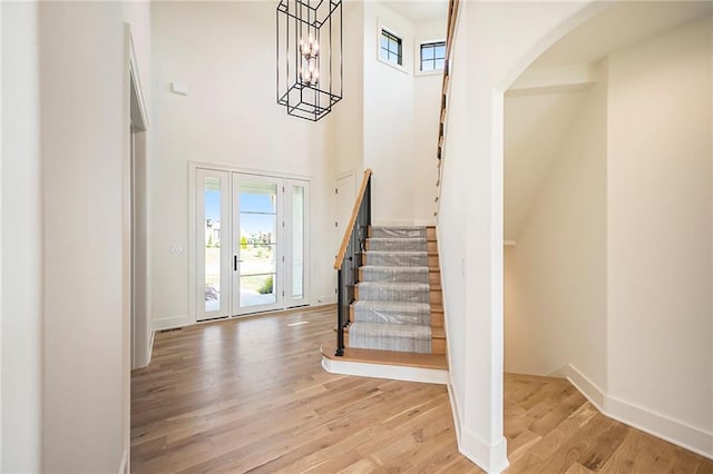 foyer with a towering ceiling, an inviting chandelier, and light hardwood / wood-style flooring