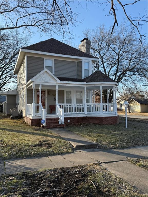 view of front facade with central AC unit, a front lawn, and covered porch