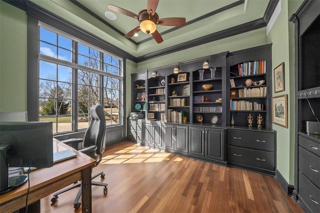 home office featuring baseboards, ceiling fan, ornamental molding, dark wood-type flooring, and a raised ceiling