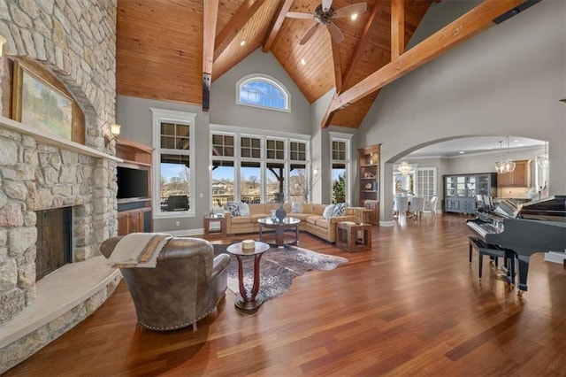 living area featuring wood finished floors, a fireplace, arched walkways, ceiling fan, and wood ceiling