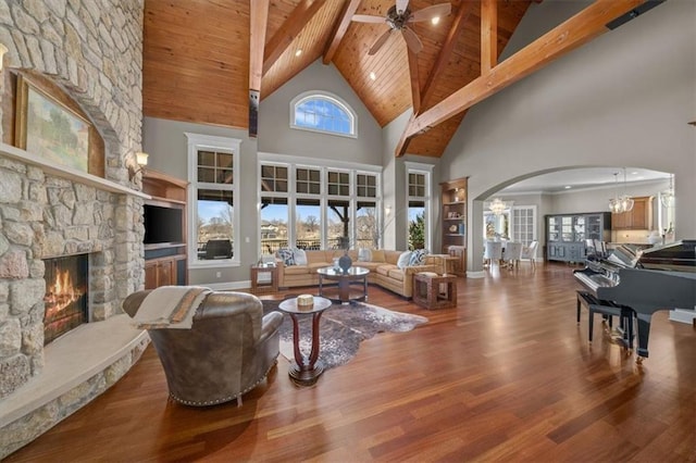 living room featuring wood finished floors, beam ceiling, a fireplace, arched walkways, and wood ceiling