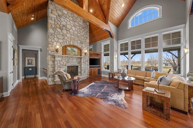 living area featuring high vaulted ceiling, wood finished floors, a stone fireplace, wooden ceiling, and baseboards