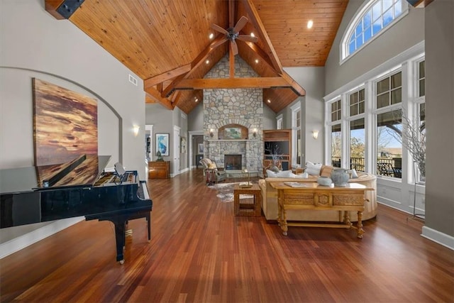 living area featuring wood finished floors, plenty of natural light, a stone fireplace, and wooden ceiling