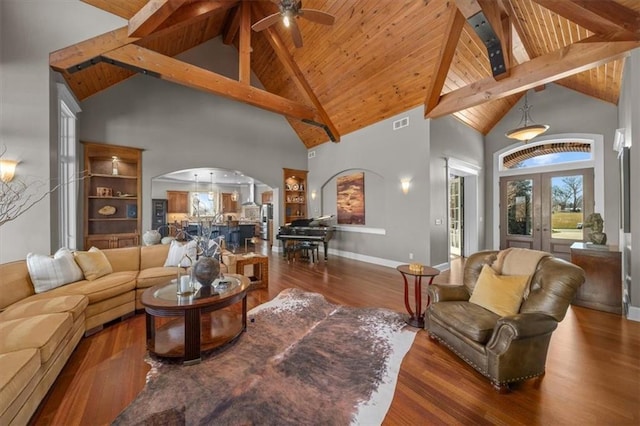 living area featuring arched walkways, beamed ceiling, and wood finished floors