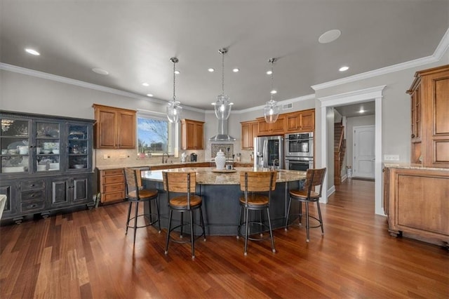 kitchen with brown cabinets, a spacious island, appliances with stainless steel finishes, and dark wood-style flooring