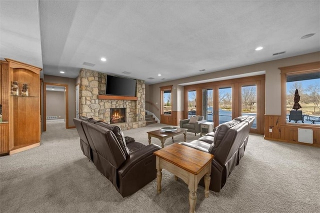 living area featuring light colored carpet, a fireplace, and a textured ceiling