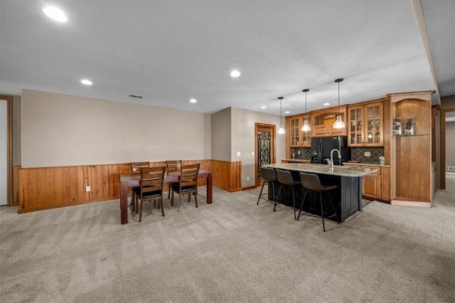 dining room with recessed lighting, a wainscoted wall, and light colored carpet