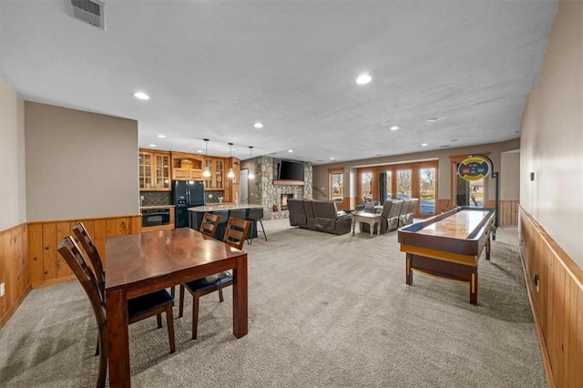 dining space featuring visible vents, light carpet, and wainscoting