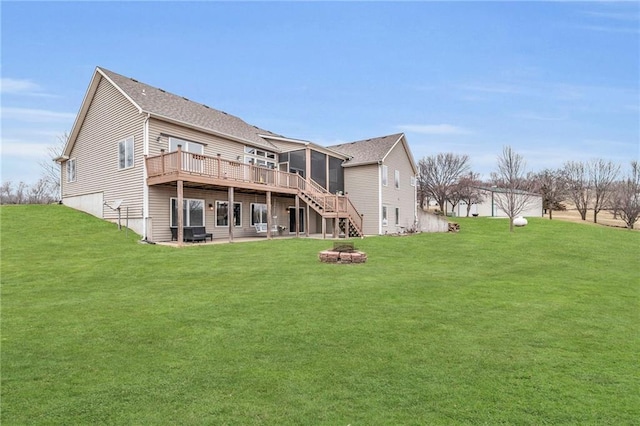 back of property featuring a lawn, a fire pit, a wooden deck, and stairs