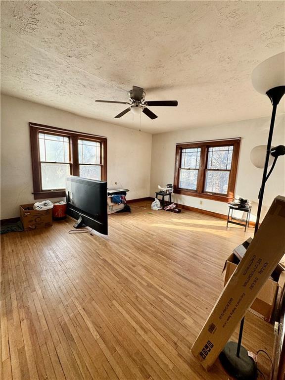 workout room featuring ceiling fan, a wealth of natural light, light hardwood / wood-style floors, and a textured ceiling