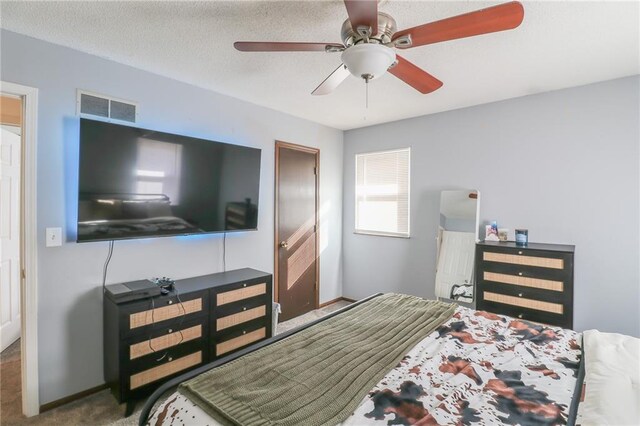 carpeted bedroom with ceiling fan and a textured ceiling