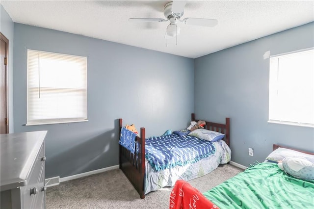 carpeted bedroom featuring ceiling fan and a textured ceiling