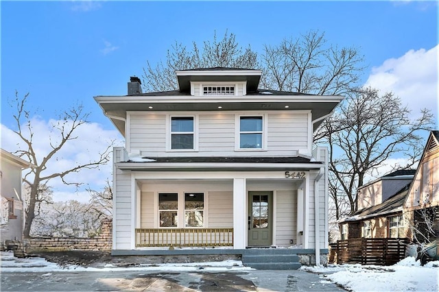 american foursquare style home featuring a porch and a chimney