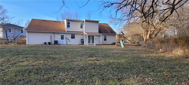 back of house featuring a playground, central air condition unit, and a lawn