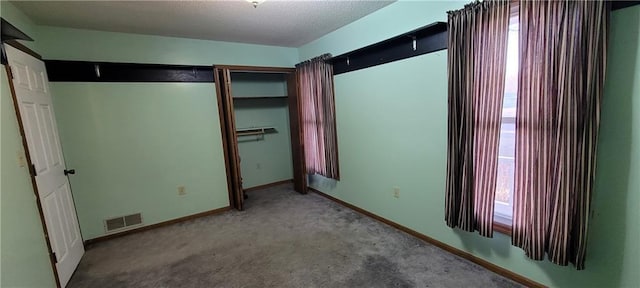 unfurnished bedroom featuring carpet, a textured ceiling, and a closet