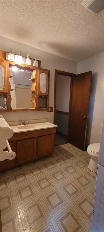 bathroom with vanity, a textured ceiling, and toilet