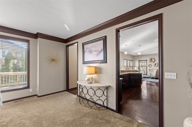 hallway with visible vents, baseboards, dark carpet, and a textured ceiling