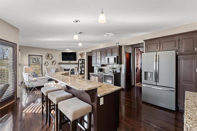 kitchen featuring visible vents, a kitchen breakfast bar, dark wood-style flooring, open floor plan, and stainless steel appliances