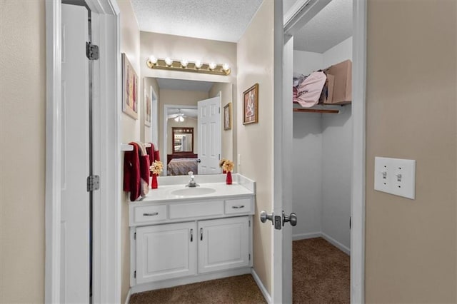 ensuite bathroom featuring ensuite bathroom, a ceiling fan, vanity, a textured ceiling, and baseboards