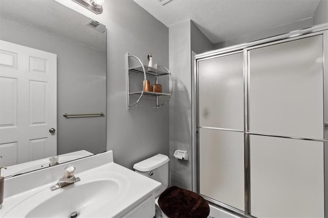 full bathroom featuring a stall shower, visible vents, toilet, a textured ceiling, and vanity