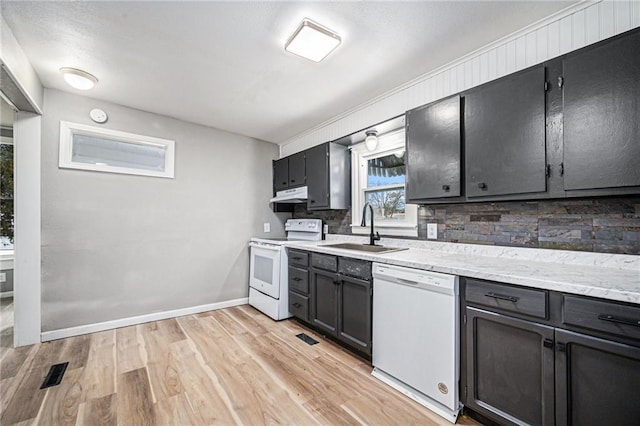 kitchen featuring sink, backsplash, light stone counters, white appliances, and light hardwood / wood-style flooring