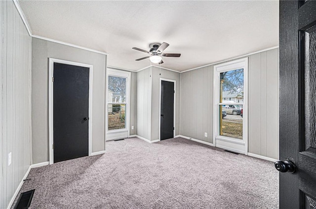 unfurnished bedroom featuring ceiling fan, light colored carpet, and ornamental molding