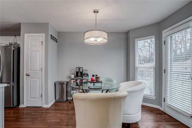 dining area with dark wood-type flooring, visible vents, and baseboards