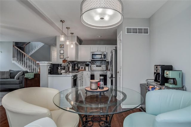 dining room with visible vents, dark wood finished floors, baseboards, and stairs