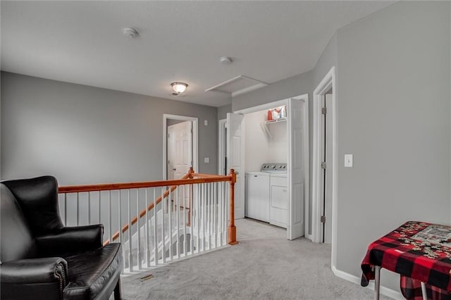 sitting room with light carpet, an upstairs landing, baseboards, washing machine and clothes dryer, and attic access