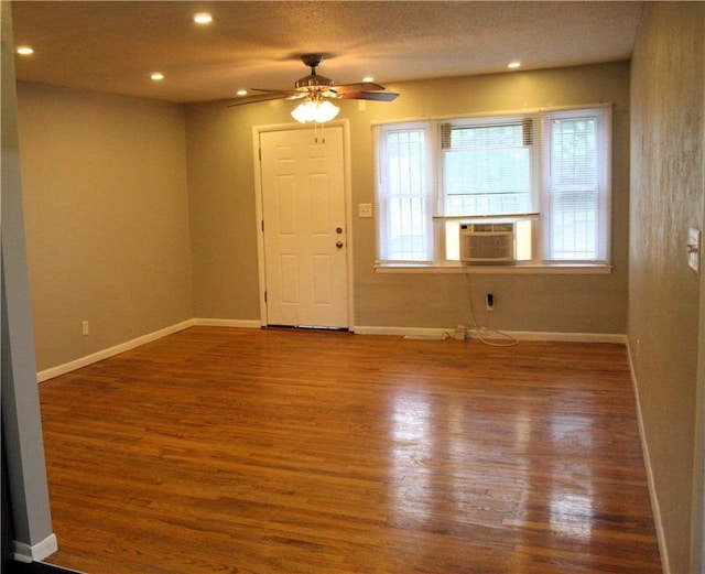 empty room featuring wood-type flooring, cooling unit, and ceiling fan