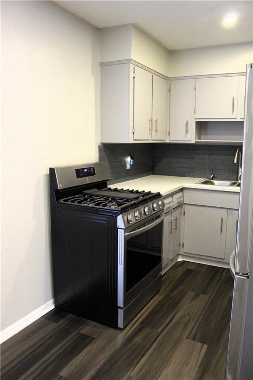 kitchen with sink, backsplash, stainless steel appliances, and white cabinets