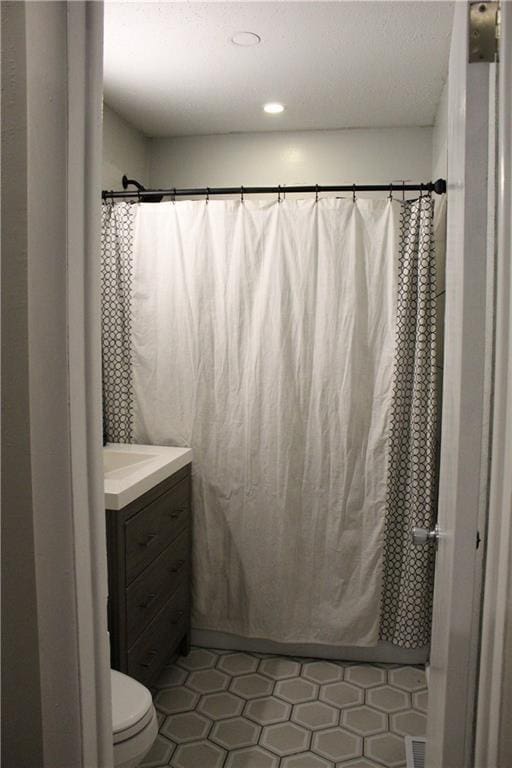 bathroom featuring a shower with curtain, vanity, toilet, and tile patterned flooring