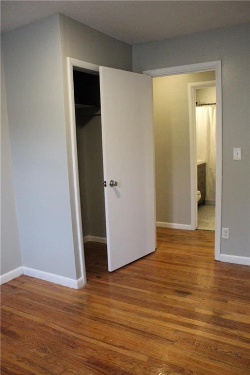 unfurnished bedroom featuring connected bathroom, hardwood / wood-style floors, and a closet