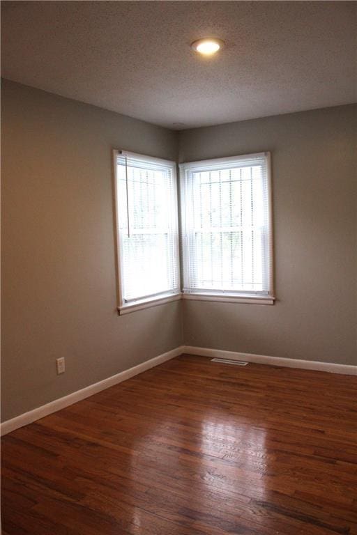 spare room with dark hardwood / wood-style flooring and a textured ceiling