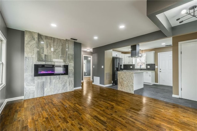 kitchen featuring dark wood-type flooring, island range hood, white cabinets, a kitchen island, and stainless steel fridge with ice dispenser