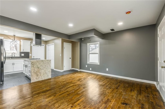 kitchen with dark hardwood / wood-style floors, white cabinets, island exhaust hood, a center island, and light stone counters